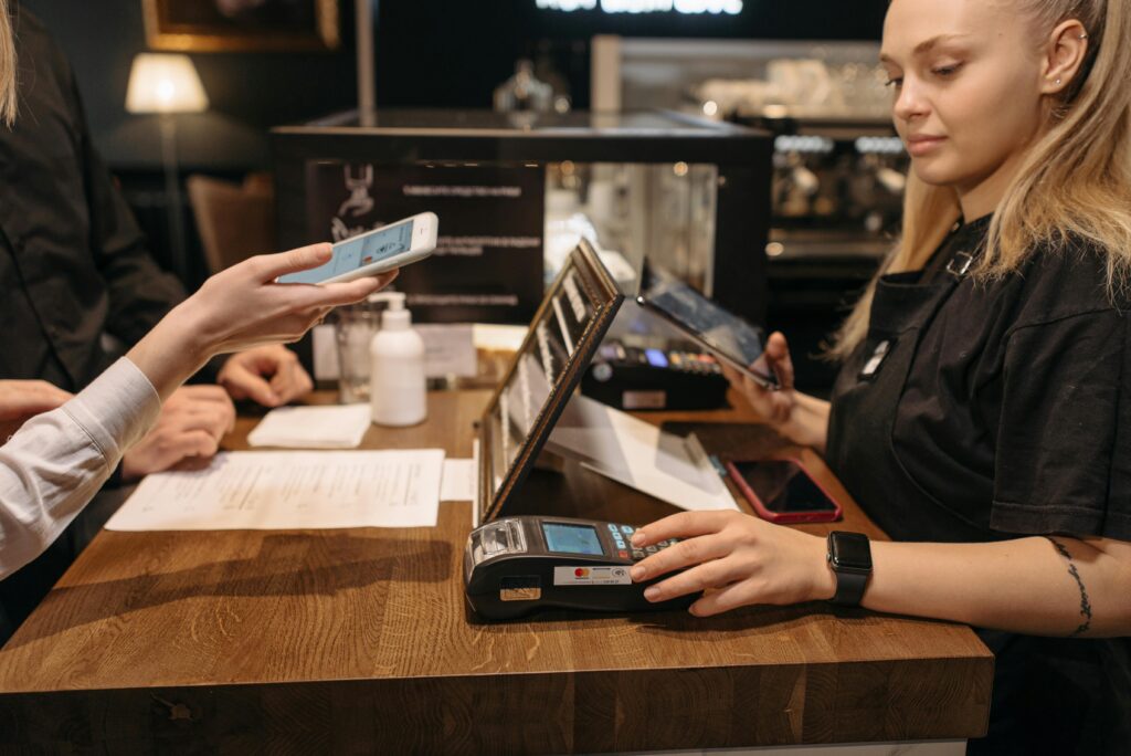 Customer making a contactless payment at the counter using a card machine.
