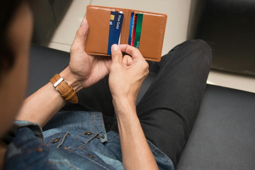 A man’s hand opening a wallet with multiple credit cards inside.