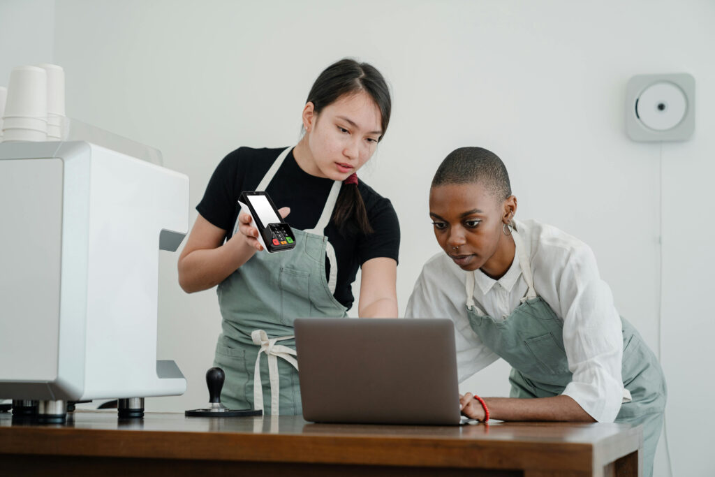 Staff member training colleague on card machine use in retail setting